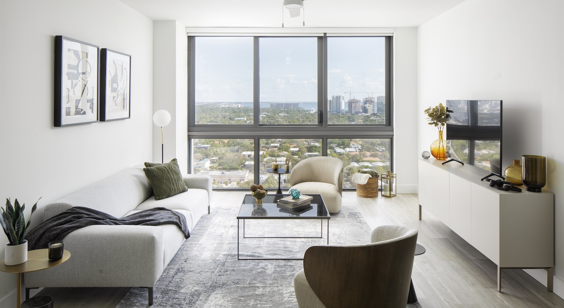 living room with large windows and a couch and coffee table in front of a tv