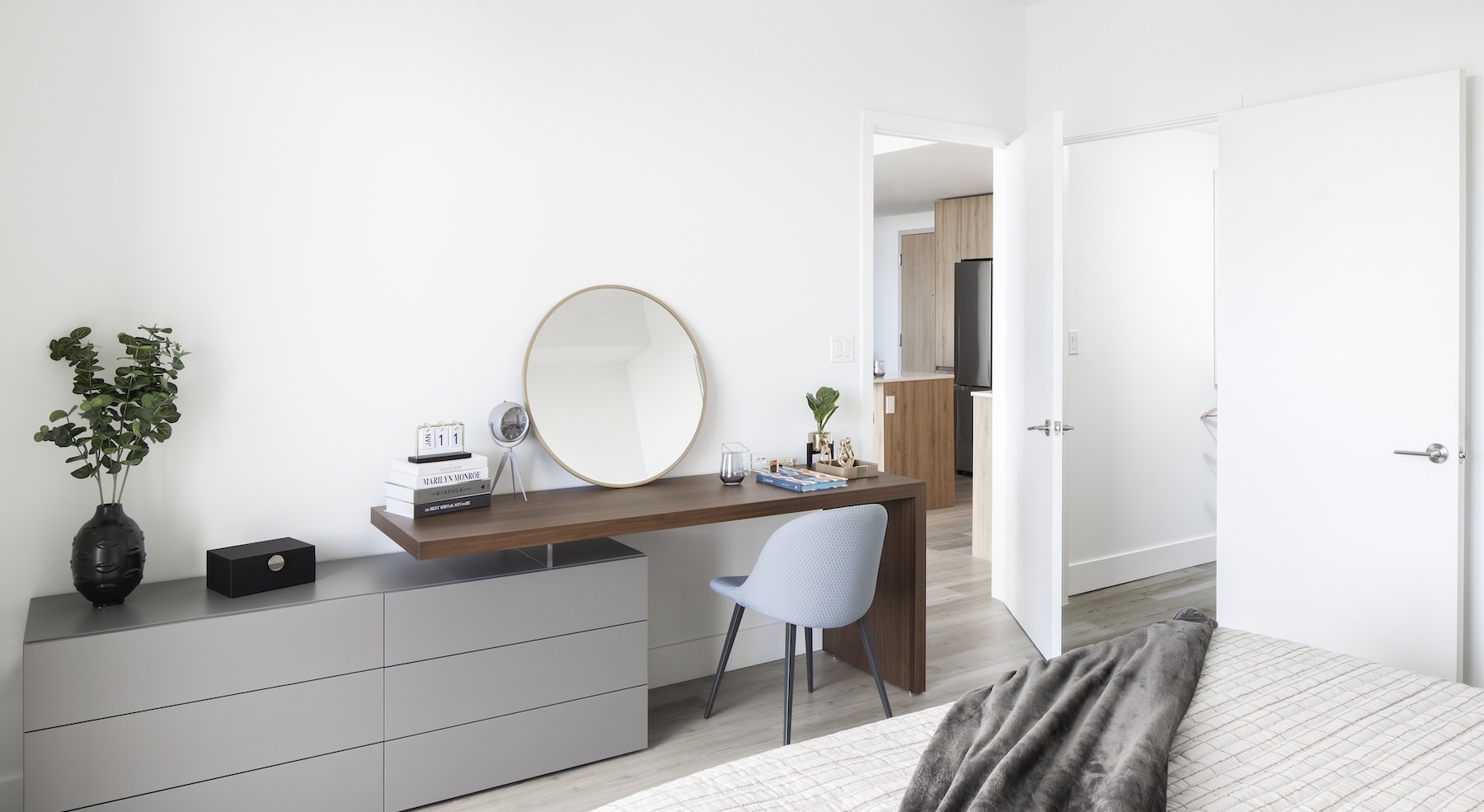 a room with a desk and chair and dresser with a plant on it