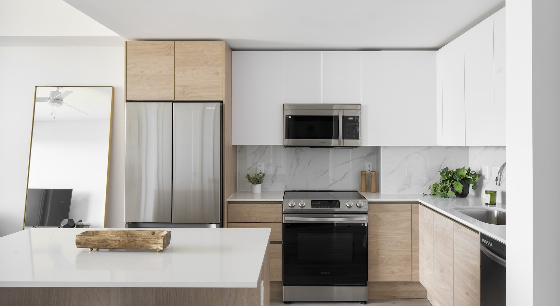 a kitchen with white cabinets a white island a stovetop a sink and a fridge