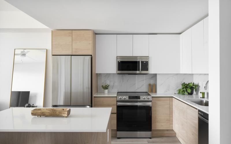 a kitchen with white cabinets a white island a stovetop a sink and a fridge